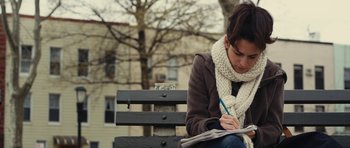 Movie still from “Obvious Child” (2014), directed by Gillian Robespierre – A woman sitting on a bench writing on a piece of paper; Close Up shot, Low angle