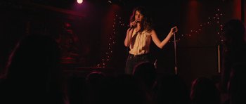 Movie still from “Obvious Child” (2014), directed by Gillian Robespierre – A woman standing on a stage holding a microphone; Medium shot, Over the shoulder angle