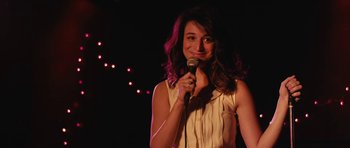 Movie still from “Obvious Child” (2014), directed by Gillian Robespierre – A woman holding a microphone while standing on a stage; Close Up shot, Over the shoulder angle