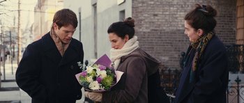 Movie still from “Obvious Child” (2014), directed by Gillian Robespierre – A woman holding a bouquet of flowers on the sidewalk; Medium shot, Over the shoulder angle