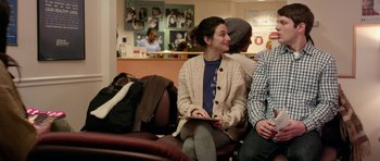 Movie still from “Obvious Child” (2014), directed by Gillian Robespierre – A woman sitting on a couch with two other people in the background; Medium shot, Over the shoulder angle