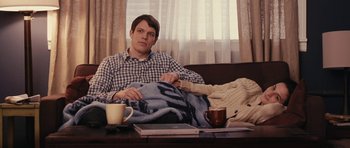 Movie still from “Obvious Child” (2014), directed by Gillian Robespierre – A man sitting at a table with a blanket; Medium shot, High angle