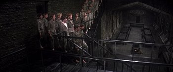 Movie still from “Oliver!” (1968), directed by Carol Reed – A group of young men standing next to each other on some stairs; Wide shot, High angle