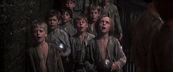 Movie still from “Oliver!” (1968), directed by Carol Reed – A group of young boys singing in a choir; Medium shot, Low angle
