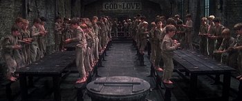 Movie still from “Oliver!” (1968), directed by Carol Reed – A group of young men standing in a room; Wide shot, High angle