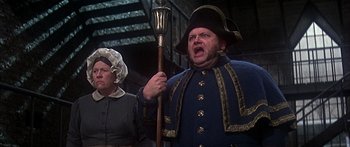 Movie still from “Oliver!” (1968), directed by Carol Reed – A man in a blue coat and a woman in a black hat; Medium shot, Low angle