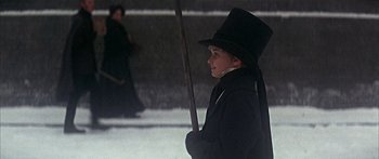 Movie still from “Oliver!” (1968), directed by Carol Reed – A young boy in a top hat holding an umbrella; Medium shot, Low angle