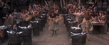 Movie still from “Oliver!” (1968), directed by Carol Reed – A group of people standing around baskets on the ground; Wide shot, High angle