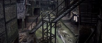 Movie still from “Oliver!” (1968), directed by Carol Reed – An old abandoned building with stairs going up to the top; Extreme Wide shot, High angle