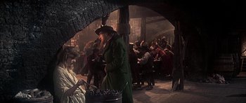 Movie still from “Oliver!” (1968), directed by Carol Reed – A group of people standing in a room; Medium shot, Over the shoulder angle