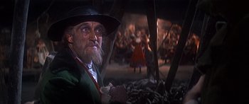 Movie still from “Oliver!” (1968), directed by Carol Reed – An old man with a beard and a hat is in front of a group of people; Close Up shot, Low angle