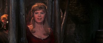 Movie still from “Oliver!” (1968), directed by Carol Reed – A woman in a red dress standing next to a tree; Close Up shot, Over the shoulder angle
