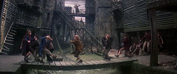 Movie still from “Oliver!” (1968), directed by Carol Reed – A group of people standing on top of a wooden bridge; Wide shot, High angle