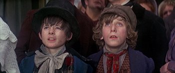Movie still from “Oliver!” (1968), directed by Carol Reed – Two young boys wearing hats and looking at something; Close Up shot, Low angle