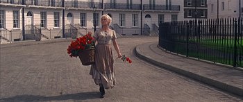 Movie still from “Oliver!” (1968), directed by Carol Reed – A woman walking down the street holding a basket of flowers; Wide shot, Low angle