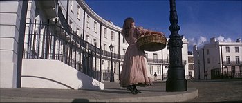 Movie still from “Oliver!” (1968), directed by Carol Reed – A woman in a dress holding a wicker basket; Wide shot, Low angle