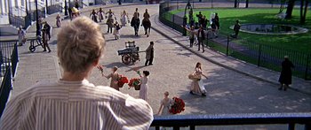 Movie still from “Oliver!” (1968), directed by Carol Reed – A group of people walking down a street with flowers; Wide shot, High angle