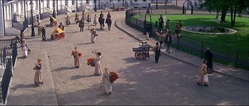Movie still from “Oliver!” (1968), directed by Carol Reed – A group of people walking down a street holding flowers; Extreme Wide shot, High angle