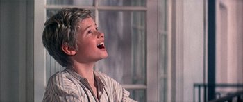 Movie still from “Oliver!” (1968), directed by Carol Reed – A young boy is smiling while sitting in a chair; Close Up shot, Low angle
