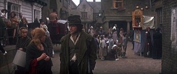 Movie still from “Oliver!” (1968), directed by Carol Reed – A crowd of people walking down a street; Wide shot, Over the shoulder angle