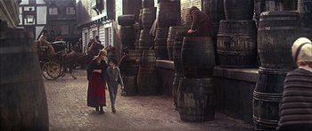 Movie still from “Oliver!” (1968), directed by Carol Reed – A group of people standing next to a bunch of wooden barrels; Wide shot, High angle