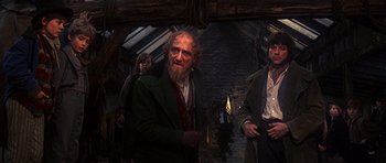 Movie still from “Oliver!” (1968), directed by Carol Reed – A group of men standing next to each other in a room; Medium shot, Over the shoulder angle