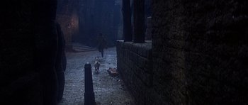 Movie still from “Oliver!” (1968), directed by Carol Reed – A man and a dog walking down a street; Wide shot, High angle