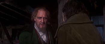 Movie still from “Oliver!” (1968), directed by Carol Reed – A man with long hair and a beard talking to another man; Close Up shot, Over the shoulder angle