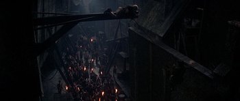 Movie still from “Oliver!” (1968), directed by Carol Reed – A crowd of people standing in a dark room; Extreme Wide shot, Overhead angle