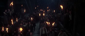 Movie still from “Oliver!” (1968), directed by Carol Reed – A group of people holding torches in the dark; Wide shot, High angle