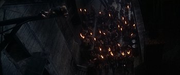 Movie still from “Oliver!” (1968), directed by Carol Reed – A group of people standing next to each other holding torches; Extreme Wide shot, Overhead angle