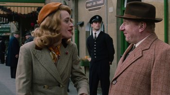 Movie still from “On Chesil Beach” (2017), directed by Dominic Cooke – A man and a woman shaking hands in front of two other men; Medium shot, Over the shoulder angle