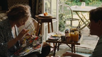 Movie still from “On Chesil Beach” (2017), directed by Dominic Cooke – A person painting a picture in a room; Medium shot, High angle