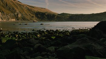 Movie still from “On Chesil Beach” (2017), directed by Dominic Cooke – A body of water surrounded by green rocks; Extreme Wide shot, High angle