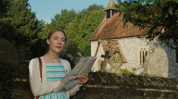 Movie still from “On Chesil Beach” (2017), directed by Dominic Cooke – A woman holding a map in front of a church; Medium shot, Low angle