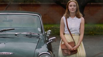 Movie still from “On Chesil Beach” (2017), directed by Dominic Cooke – A woman standing in front of an old fashioned car; Medium shot, Low angle