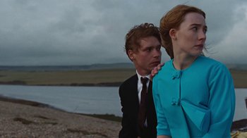 Movie still from “On Chesil Beach” (2017), directed by Dominic Cooke – A man and a woman standing next to each other on a beach; Medium shot, Over the shoulder angle