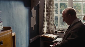 Movie still from “On Chesil Beach” (2017), directed by Dominic Cooke – An older man sitting in front of a window; Medium shot, Over the shoulder angle