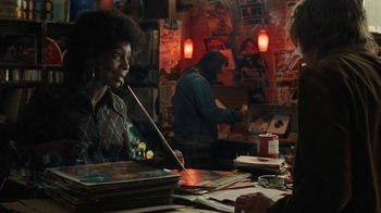 Movie still from “On Chesil Beach” (2017), directed by Dominic Cooke – A woman sitting at a table in front of a bunch of papers; Medium shot, Over the shoulder angle