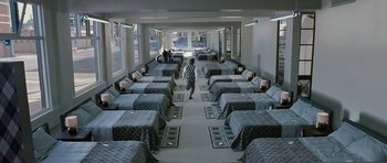 Movie still from “Mr. Nobody” (2009), directed by Jaco Van Dormael – A room filled with beds and people walking on the floor; Wide shot, High angle