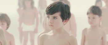 Movie still from “Mr. Nobody” (2009), directed by Jaco Van Dormael – A young boy with short black hair and blue eyes looking at the camera; Close Up shot, Over the shoulder angle