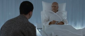Movie still from “Mr. Nobody” (2009), directed by Jaco Van Dormael – An older man in a hospital bed holding a nintendo wii game controller; Medium shot, Over the shoulder angle