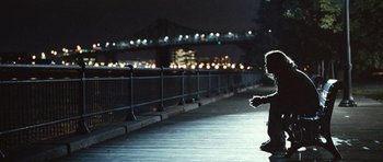 Movie still from “Mr. Nobody” (2009), directed by Jaco Van Dormael – A man sitting on a skateboard on a boardwalk at night; Wide shot, Over the shoulder angle