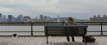 Movie still from “Mr. Nobody” (2009), directed by Jaco Van Dormael – A person sitting on a bench looking out at a city; Wide shot, Over the shoulder angle