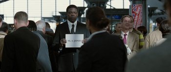 Movie still from “Mr. Nobody” (2009), directed by Jaco Van Dormael – A man in a suit and tie holding up a sign; Medium shot, Over the shoulder angle