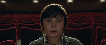 Movie still from “Mr. Nobody” (2009), directed by Jaco Van Dormael – A young boy is sitting in a movie theater; Close Up shot, High angle