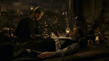 Movie still from “Once Upon a Time in America” (1984), directed by Sergio Leone – Two men are sitting on a bed in a room with lights; Wide shot, High angle