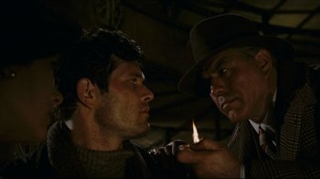 Movie still from “Once Upon a Time in America” (1984), directed by Sergio Leone – A man lighting a cigarette next to another man in a hat; Close Up shot, Over the shoulder angle