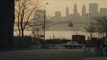 Movie still from “Once Upon a Time in America” (1984), directed by Sergio Leone – A car driving down a street next to a street light; Extreme Wide shot, High angle