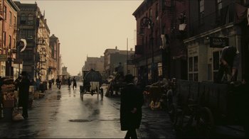 Movie still from “Once Upon a Time in America” (1984), directed by Sergio Leone – A man walking down a street with a horse drawn carriage; Wide shot, High angle